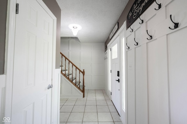 foyer with a textured ceiling, light tile patterned floors, and stairway