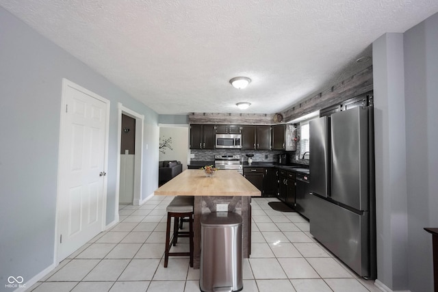 kitchen featuring wooden counters, a breakfast bar, stainless steel appliances, and a textured ceiling