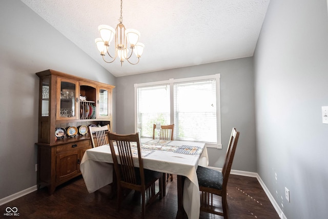 dining area featuring a textured ceiling, an inviting chandelier, lofted ceiling, and dark wood-type flooring