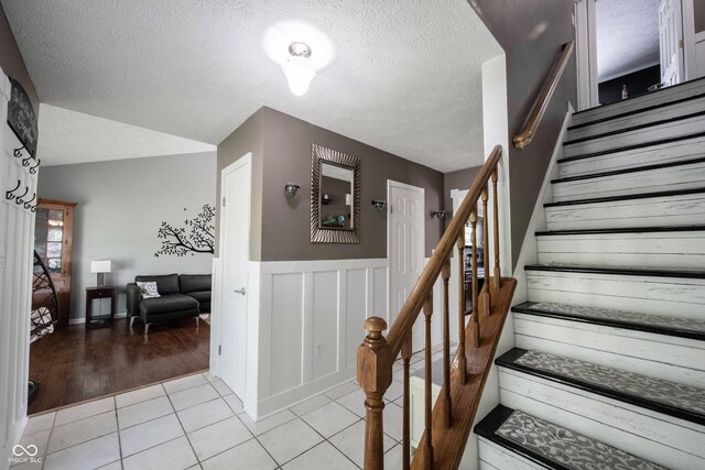 stairs featuring a textured ceiling, wainscoting, and tile patterned flooring