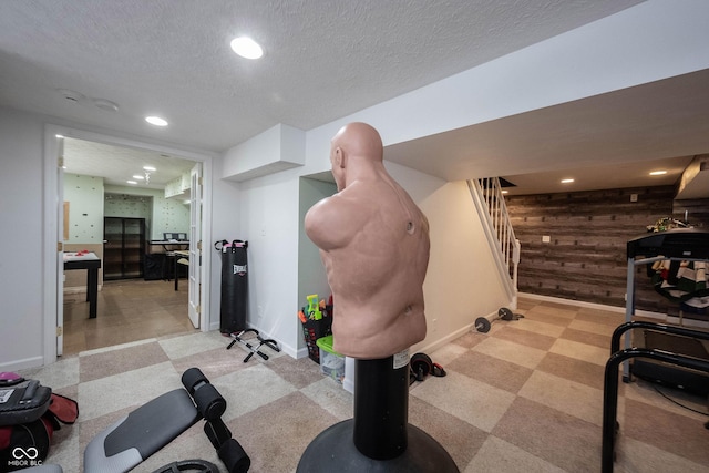 workout room featuring a textured ceiling, baseboards, wood walls, and recessed lighting