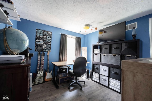 office featuring visible vents, a textured ceiling, and wood finished floors