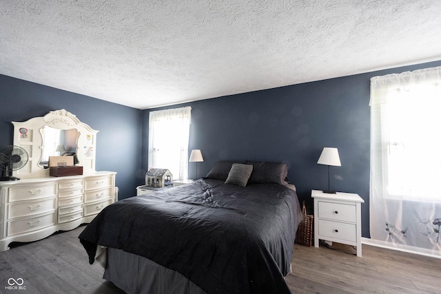 bedroom with baseboards, a textured ceiling, and wood finished floors