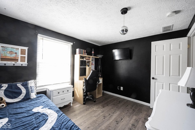 bedroom with a textured ceiling, visible vents, and wood finished floors
