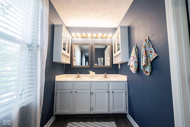 full bathroom with baseboards, a sink, a textured ceiling, and wood finished floors