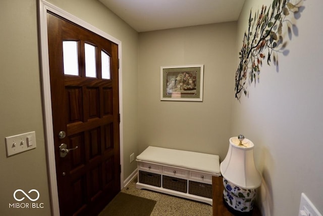 foyer featuring speckled floor and baseboards