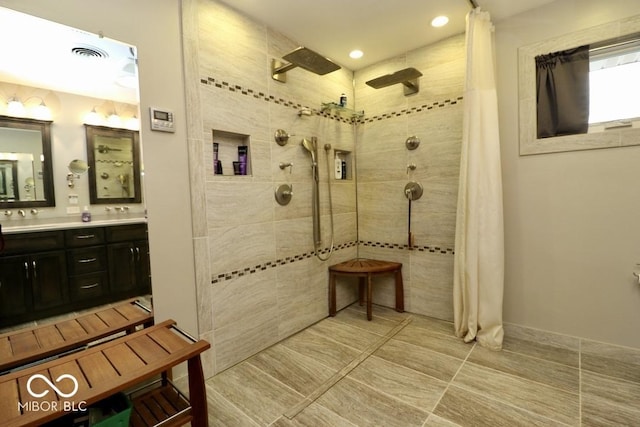 full bath featuring visible vents, recessed lighting, double vanity, and a tile shower