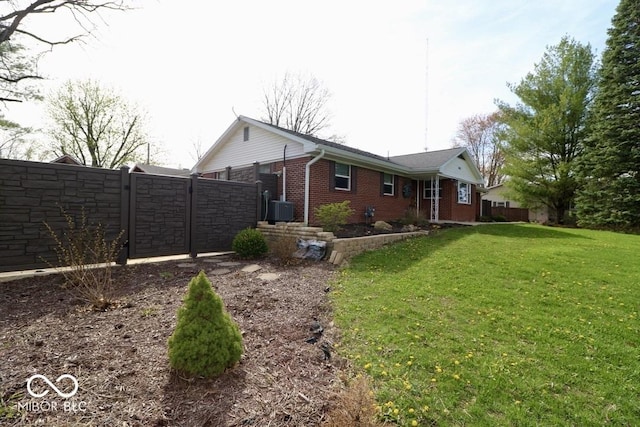 rear view of property with central AC, a gate, fence, a yard, and brick siding