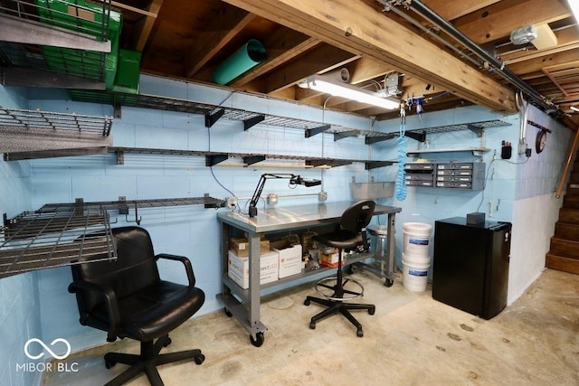 unfinished basement featuring concrete block wall and stairway