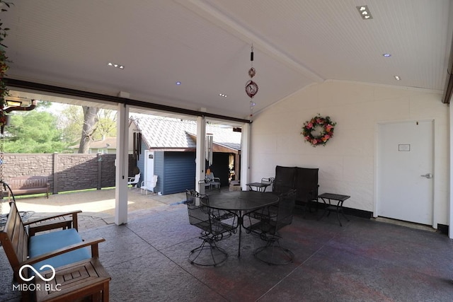 view of patio / terrace featuring fence, outdoor dining area, an outdoor structure, and a storage shed