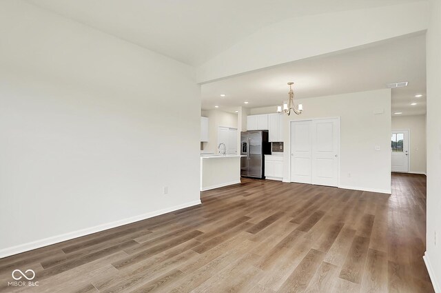 2764 Glade Ave, Plainfield, IN 46168 - unfurnished living room featuring a chandelier, wood finished floors, baseboards, recessed lighting, and a sink