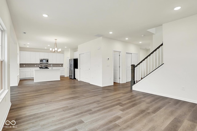 2764 Glade Ave, Plainfield, IN 46168 - unfurnished living room with a chandelier, recessed lighting, light wood-type flooring, stairs, and baseboards