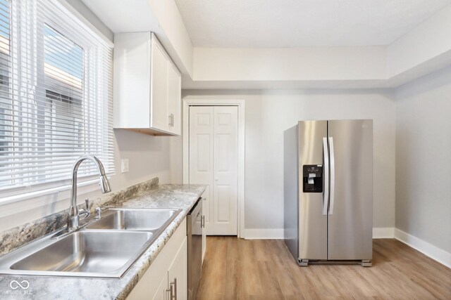 2114 N Dexter St, Indianapolis, IN 46202 - kitchen featuring stainless steel appliances, a sink, baseboards, light wood-style flooring, and white cabinetry