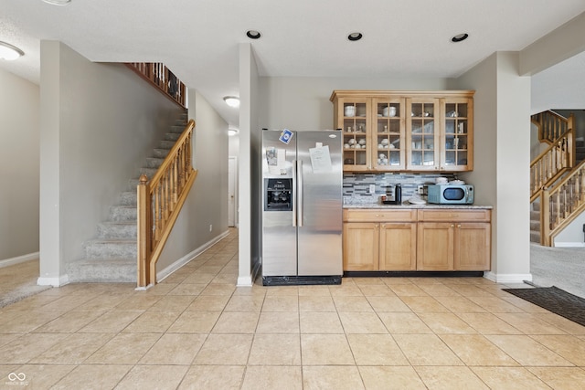 621 Fireside Dr, Greenwood, IN 46143 - kitchen with stainless steel fridge with ice dispenser, decorative backsplash, light tile patterned floors, glass insert cabinets, and baseboards
