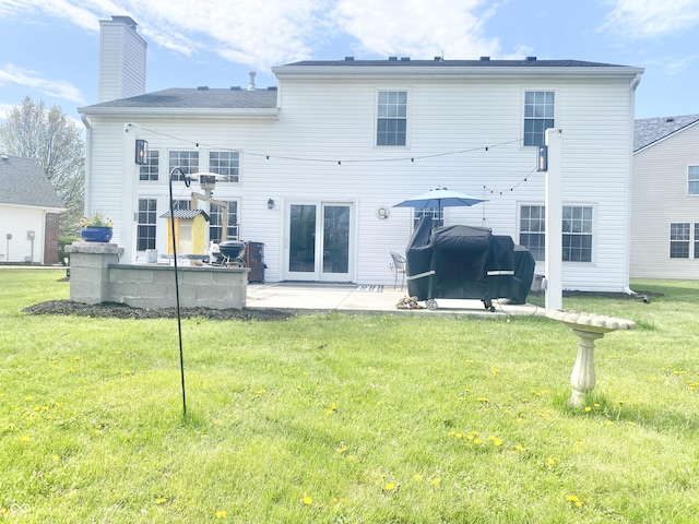 back of house featuring a lawn, a chimney, and a patio