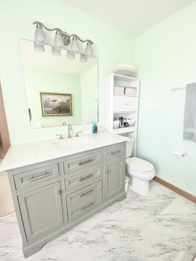 bathroom with baseboards, marble finish floor, vanity, and toilet