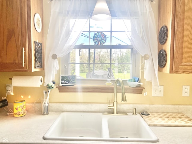 interior details with brown cabinetry, light countertops, and a sink