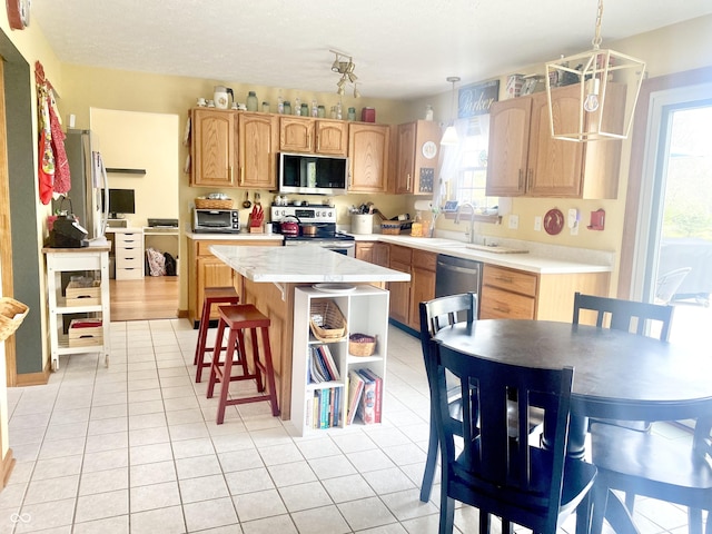 kitchen with stainless steel appliances, light countertops, a kitchen island, and plenty of natural light