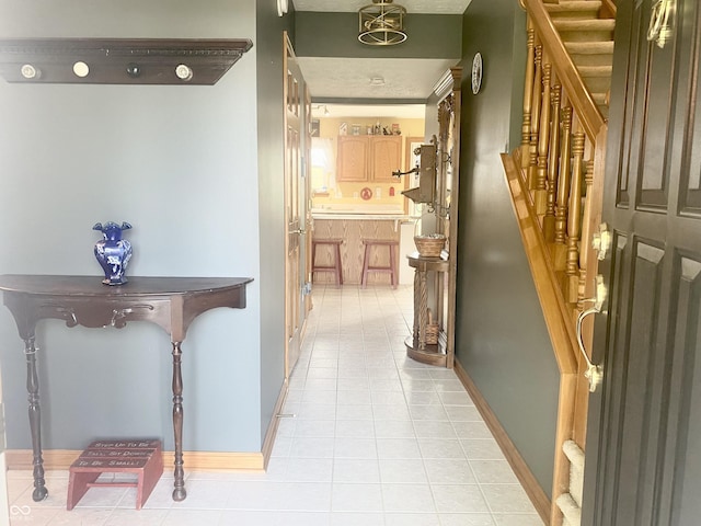 hall with baseboards, stairway, and light tile patterned flooring