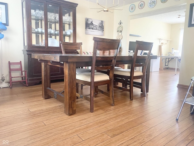 dining area with light wood-type flooring and an inviting chandelier