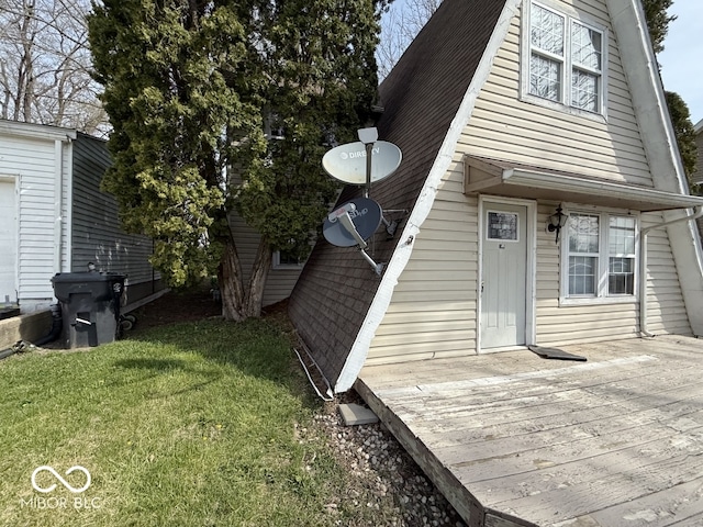 exterior space with a lawn, a wooden deck, a gambrel roof, and roof with shingles