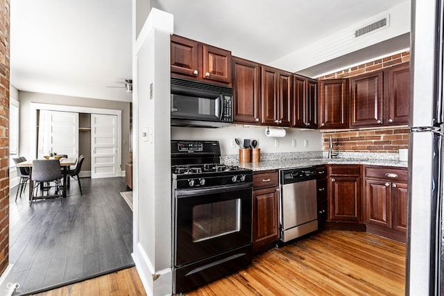 801 N Pennsylvania St Apt D, Indianapolis, IN 46204 - kitchen featuring black appliances, light wood-style floors, light stone countertops, a sink, and a ceiling fan