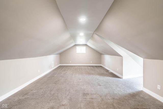 additional living space with vaulted ceiling, visible vents, carpet flooring, and baseboards