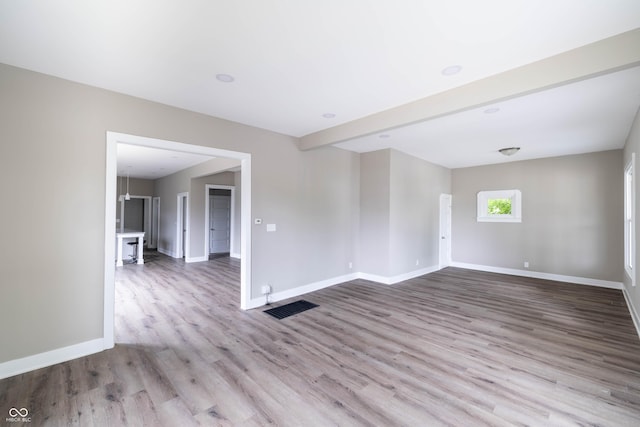 empty room featuring visible vents, wood finished floors, and baseboards