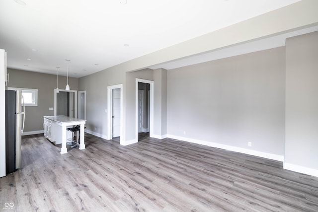 unfurnished living room with baseboards and wood finished floors