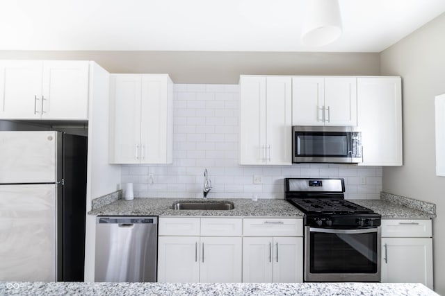 kitchen featuring backsplash, appliances with stainless steel finishes, white cabinetry, and a sink
