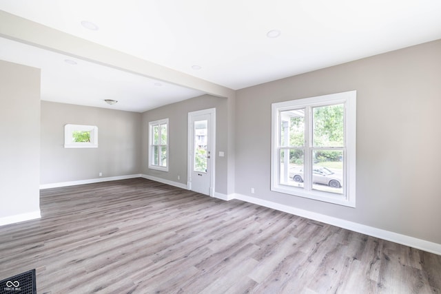 unfurnished living room with wood finished floors, baseboards, and a wealth of natural light