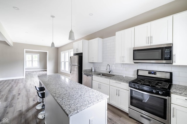 kitchen with tasteful backsplash, wood finished floors, a sink, stainless steel appliances, and white cabinets
