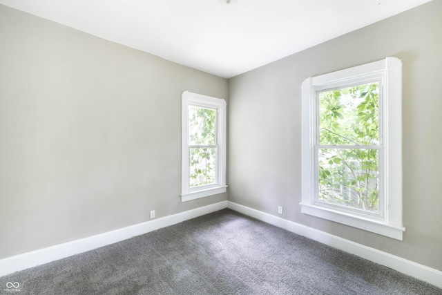 unfurnished room featuring dark carpet and baseboards
