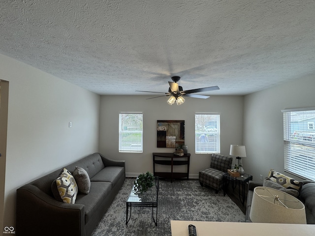 carpeted living area with baseboards, a ceiling fan, and a textured ceiling