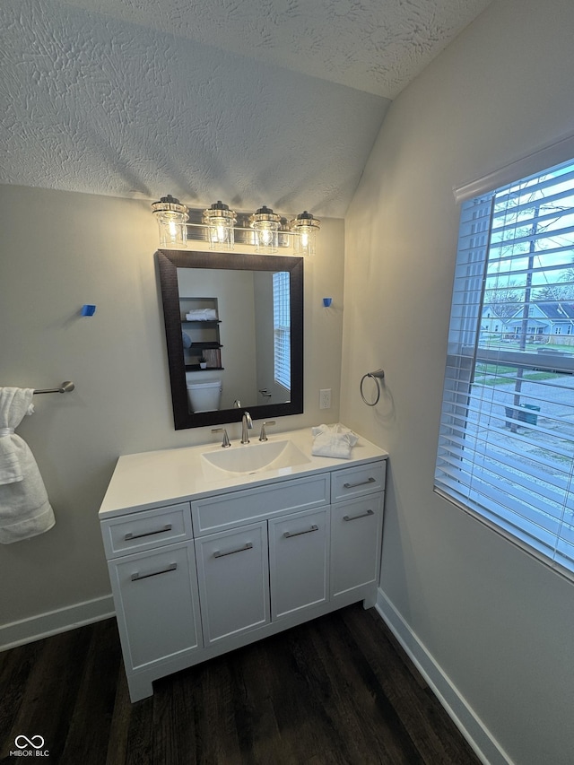 bathroom featuring wood finished floors, a textured ceiling, lofted ceiling, and baseboards