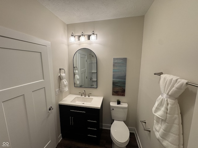 bathroom with toilet, vanity, a textured ceiling, and baseboards