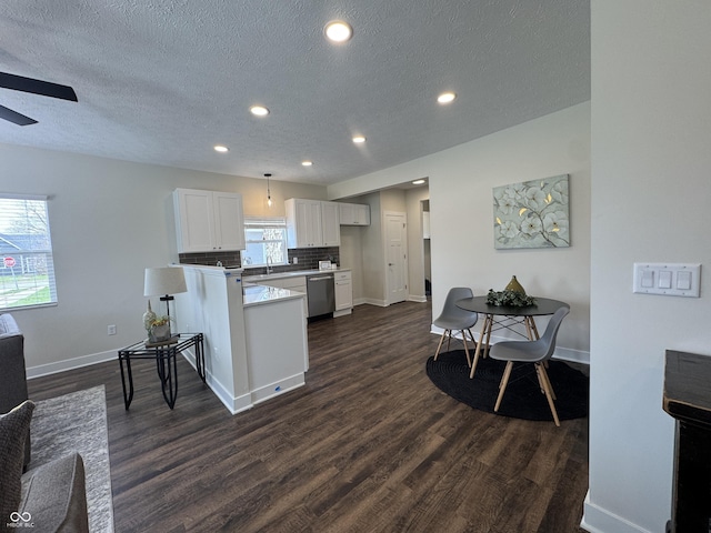 kitchen featuring white cabinets, a peninsula, light countertops, dishwasher, and dark wood-type flooring