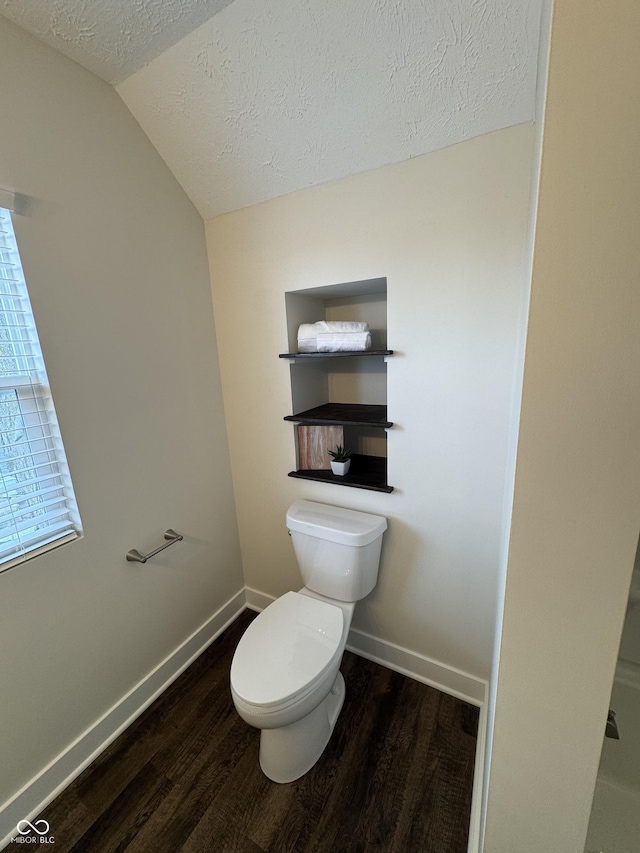 bathroom with vaulted ceiling, wood finished floors, a textured ceiling, and toilet