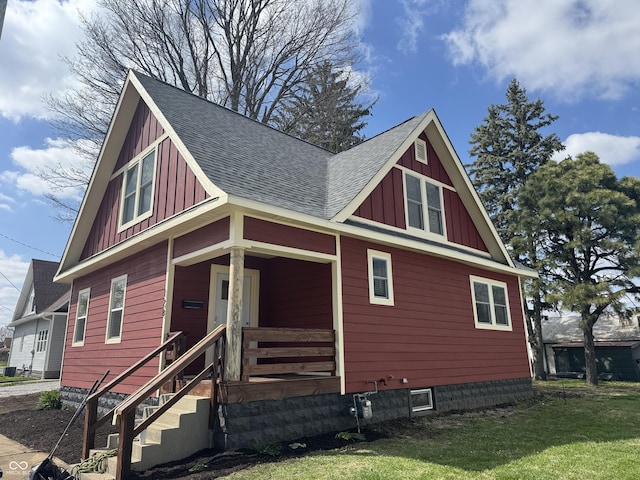 view of front facade featuring board and batten siding, a porch, a shingled roof, and a front lawn