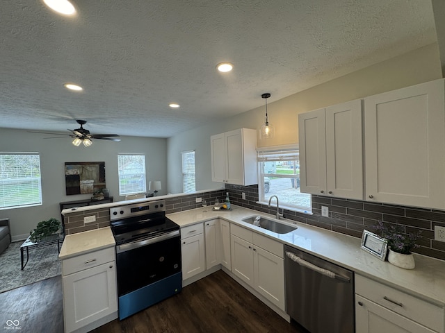 kitchen with a sink, decorative backsplash, stainless steel appliances, dark wood finished floors, and a peninsula