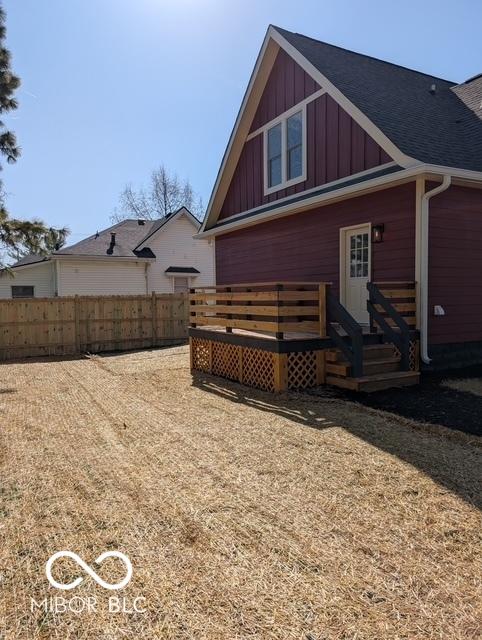 back of house featuring board and batten siding, fence, and a deck