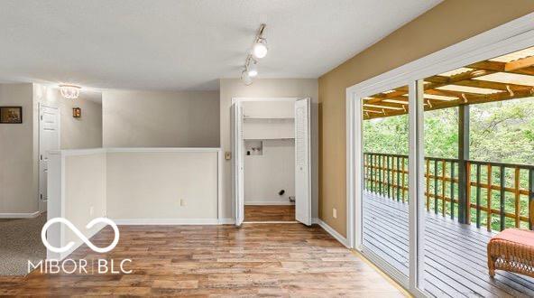 spare room with rail lighting, baseboards, and wood finished floors