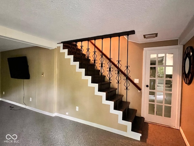 stairs featuring baseboards, a textured ceiling, and visible vents