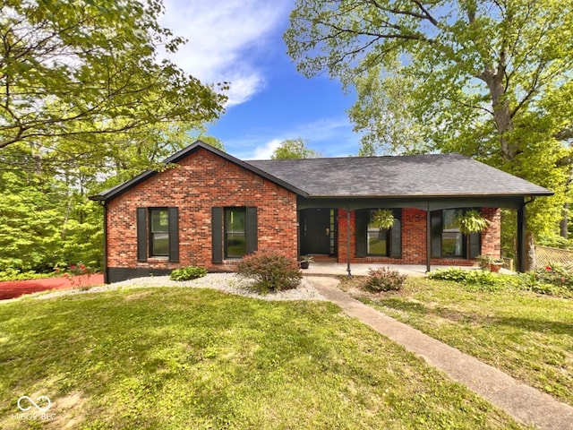 ranch-style home with a shingled roof, a front lawn, and brick siding