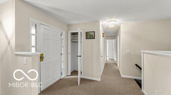 foyer featuring carpet floors, a textured ceiling, and baseboards