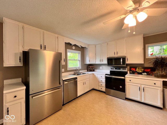 kitchen featuring appliances with stainless steel finishes, a sink, white cabinetry, and light countertops