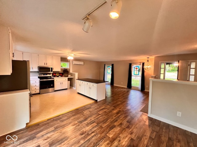 kitchen featuring dark wood-style floors, open floor plan, white cabinetry, a ceiling fan, and appliances with stainless steel finishes