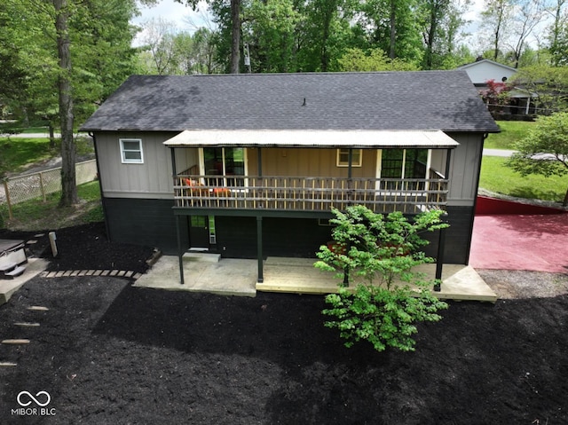 back of property featuring roof with shingles, fence, and a deck