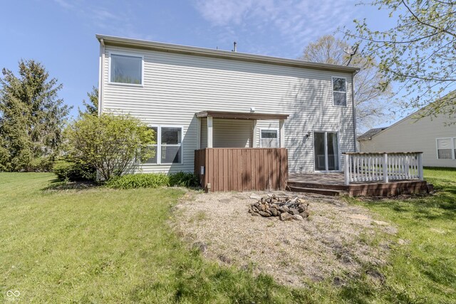 rear view of house featuring a lawn, a deck, and a fire pit