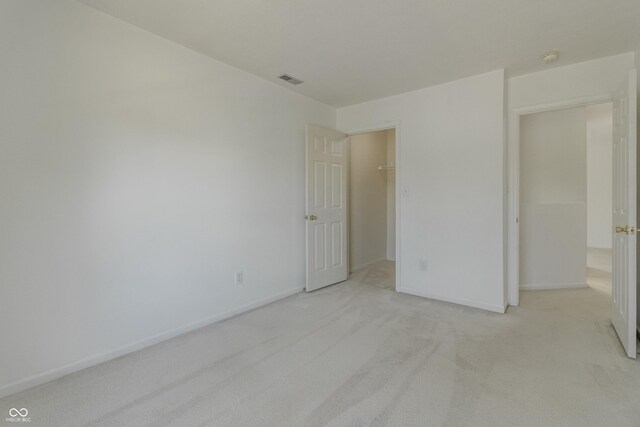 unfurnished bedroom with visible vents, baseboards, a spacious closet, and light carpet